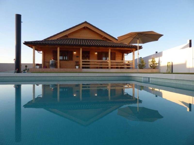 Una casa de madera de diseño moderno con piscina y porche